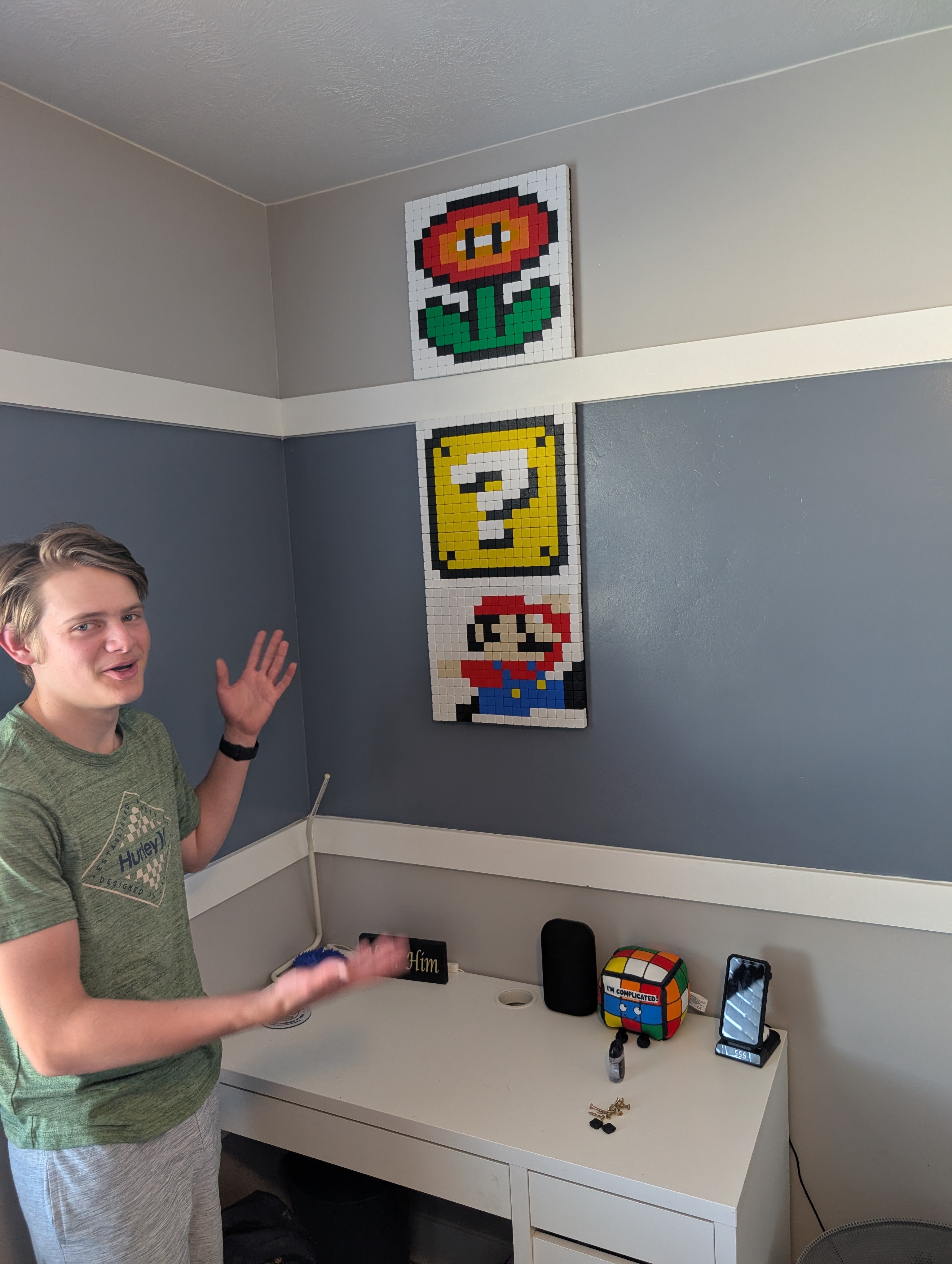 A Klixel maker showing finished pixel art mounted on a bedroom wall