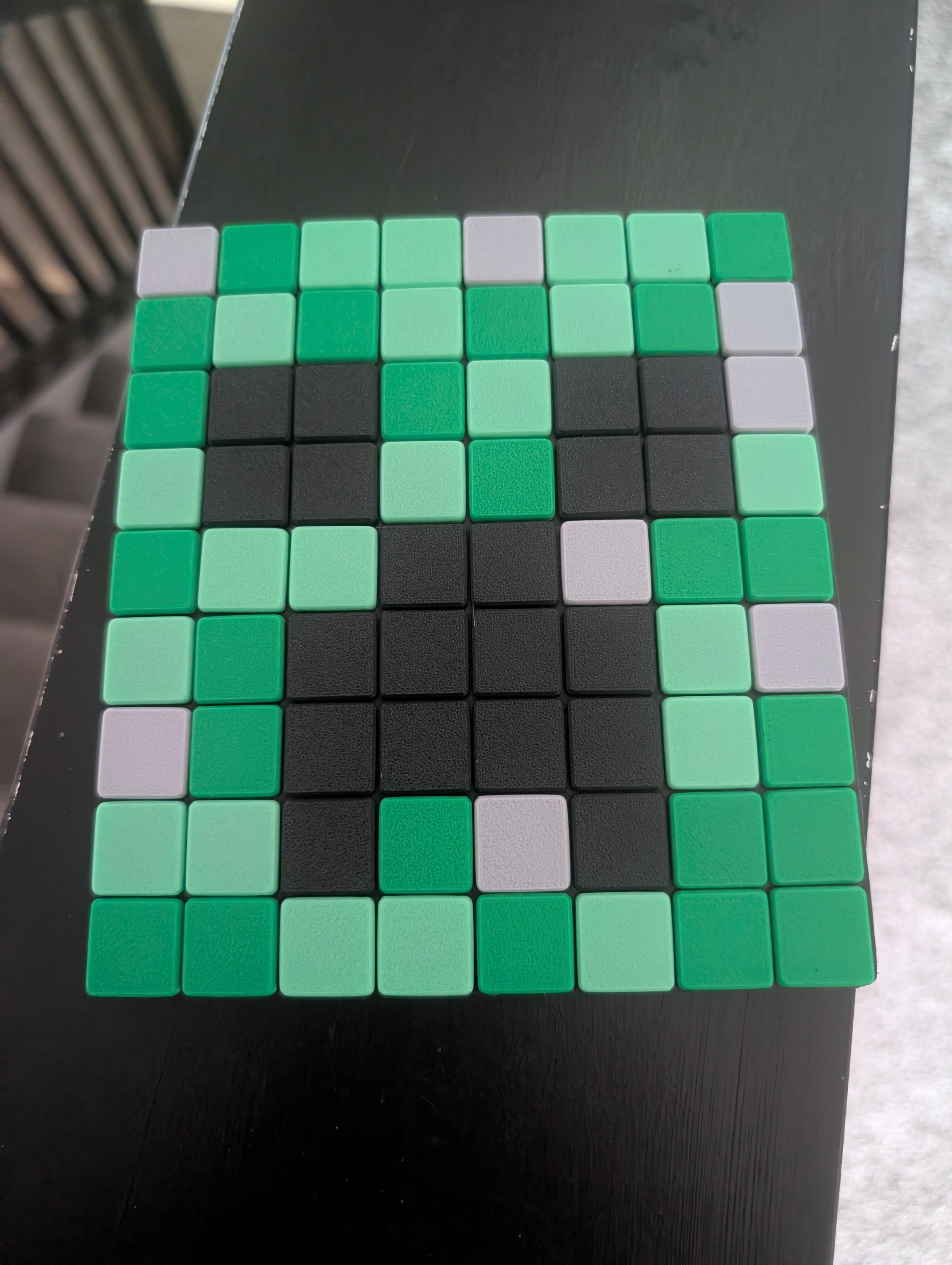 Close-up of real green, mint, black and white Klixel pieces snapped into a grid